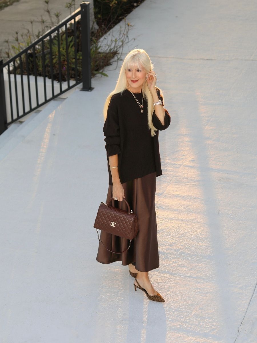 Woman in a monochromatic brown outfit poses outside at sunset.