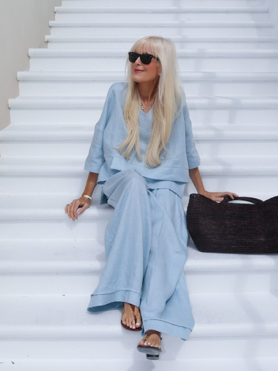 Mary Murnane in light blue 100% european linen from LINTICO set sitting on white stairs.