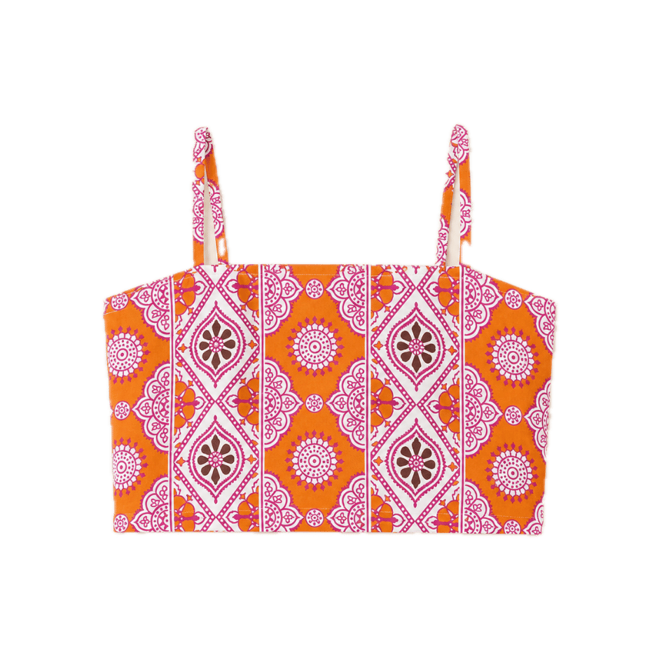A vibrant orange and pink block-print crop top with spaghetti straps and a straight bandeau neckline. Features a medallion-style geometric print in pink and white against a bold orange ground.