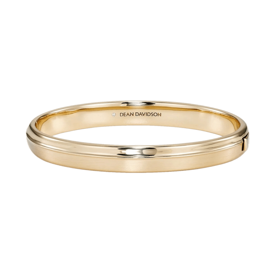 A polished gold bangle bracelet by Dean Davidson with a smooth, rounded profile and a subtle engraved channel running along the center. Sleek and minimalist with a hinged opening.