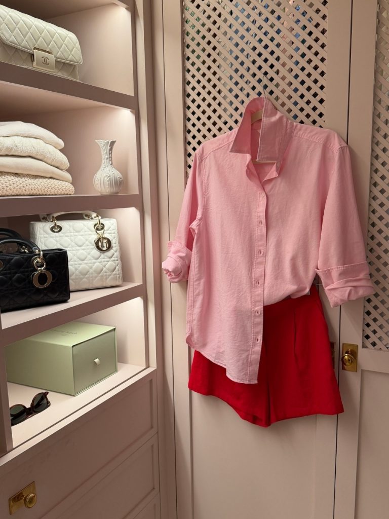 Mary's casual Friday summer outfit featuring a light pink button-down shirt tucked into tailored red shorts, creating a polished and classic warm-weather look with timeless style.